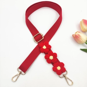 Detail of red adjustable fabric strap with handcrafted crochet flowers and gold hardware