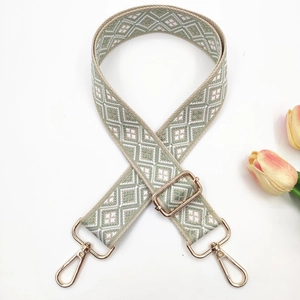 Detail of sage green geometric jacquard bag strap with pale gold metal hardware