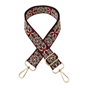 Detail of ethnic style woven bag strap with red geometric embroidery and gold metal clips