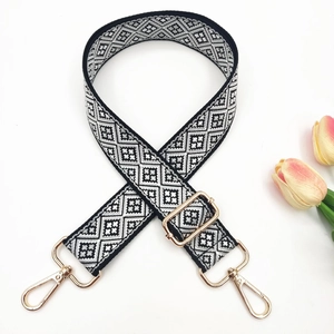 Close-up of black and white geometric jacquard bag strap with gold metal hardware