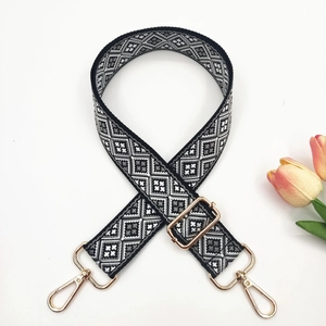 Close-up of adjustable jacquard bag strap with geometric patterns and gold metal clips