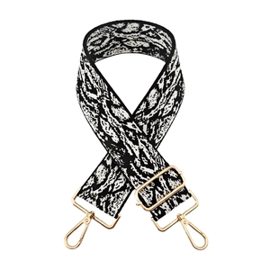 Detail of adjustable wide bag strap with black and white jacquard pattern and gold hardware