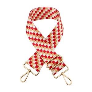 Close-up of red and gold checkered woven bag strap with golden metal lobster clasps