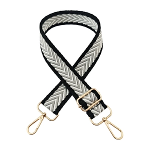 Close-up of black and white chevron jacquard bag strap with gold metal lobster clasps