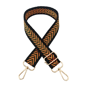 Detail of adjustable woven bag strap with orange-green V-pattern and gold metal hooks