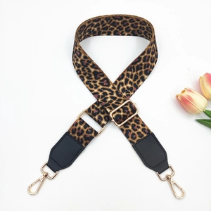 Detail of adjustable leopard print bag strap with gold metal hooks on white background