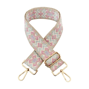 Macro view of geometric ethnic embroidery on adjustable jacquard strap with gold metal hooks