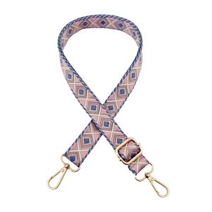 Detail of bohemian geometric woven strap with pink and blue diamond patterns and gold hooks