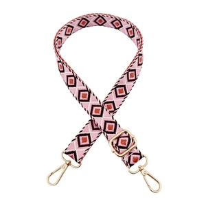 Detail of bohemian jacquard woven strap with pink geometric patterns and gold metal hooks