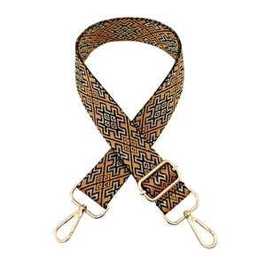 Macro detail of geometric jacquard bag strap with gold lobster clasps and metal hardware