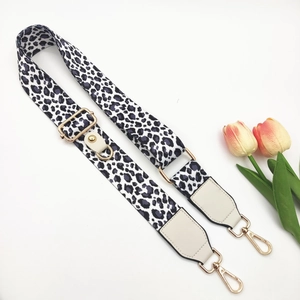 Detail of leopard print wide strap with gold swivel hooks and beige faux leather ends