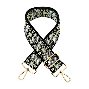 Close-up of geometric ethnic embroidery on adjustable wide strap with gold metal hooks