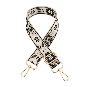 Close-up of ethnic embroidered bag strap with floral pattern and gold metal buckles