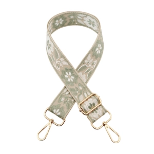 Close-up of floral embroidered bag strap with sage green weaving and gold metal hooks