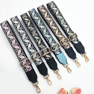Flat lay of colorful jacquard guitar style bag straps with leaf pattern and gold buckles