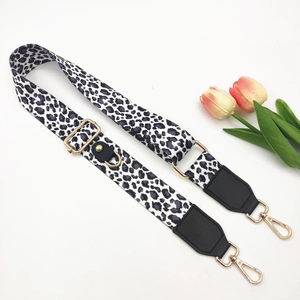 Close-up of leopard print polyester strap with adjustable gold hooks and black leather