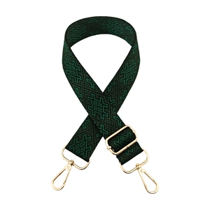 Detail of dark green woven guitar strap with black geometric patterns and gold metal hooks