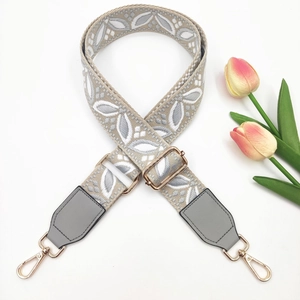 Detailed view of gray floral jacquard strap with leather ends and gold metal hooks