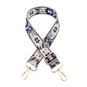Detail of adjustable floral embroidery bag strap with gold metal hooks and blue weaving