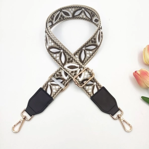 Detail of bohemian jacquard wide bag strap with brown leather and gold hardware