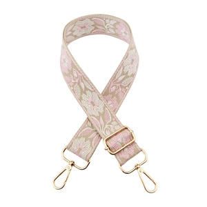 Close-up of floral embroidered bag strap with light gold metal swivel hooks and adjuster