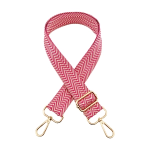 Detail of pink and white wave pattern bag strap with adjustable gold metal hardware buckle