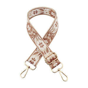 Detail of bohemian floral embroidery on wide strap with polished gold metal buckles