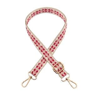 Detail of pink and red geometric woven bag strap with golden lobster clasps