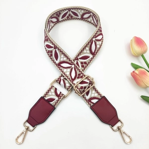 Detail of burgundy ethnic jacquard strap with leaf pattern and golden metal buckles