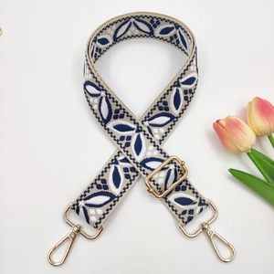 Gros plan de la bandoulière ethnique en jacquard avec broderie beige et clips dorés