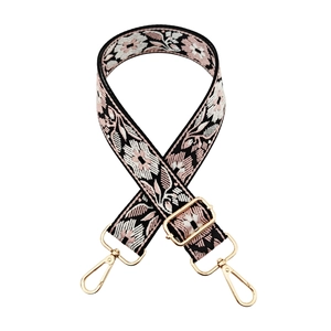 Macro view of wide jacquard bag strap with floral weave and gold lobster clasps