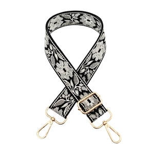 Detail of floral embroidered bag strap with gold metal hardware and adjustable buckle