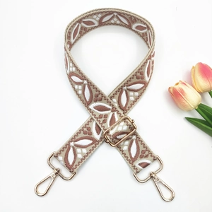 Détail d'une bandoulière boho brodée avec motif de feuilles et boucles dorées