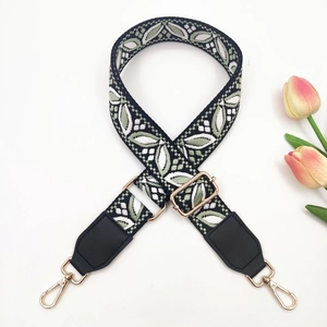 Detail of bohemian jacquard bag strap with white green leaves and golden hardware
