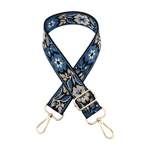 Close-up of ethnic floral embroidery on a wide bag strap with gold metal hooks