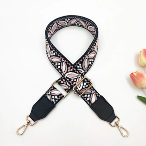 Detail of jacquard woven bag strap with pink leaf pattern and gold metal lobster clasps