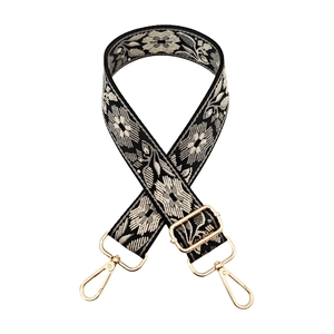 Detail of floral jacquard embroidery pattern and gold metal hardware on bag strap