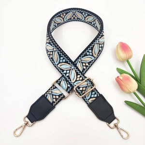 Close-up of ethnic jacquard shoulder strap with gold metal hooks and floral accents