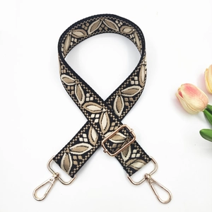 Détail de la bandoulière en jacquard brodé avec motif de feuilles et boucles dorées