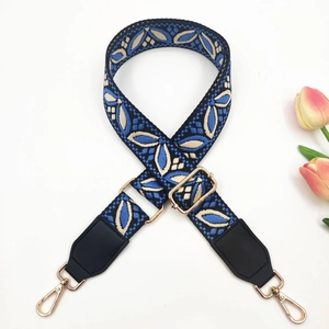 Close-up of bohemian floral jacquard bag strap with leather ends and golden metal clips
