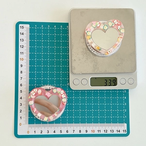 Macro shot of a pink heart-shaped phone grip and makeup mirror showing size and weight