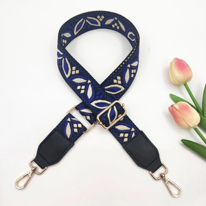 Close-up of ethnic jacquard purse strap with white floral pattern and gold metal hooks