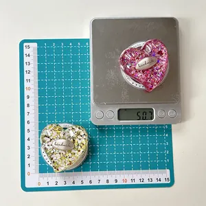 Close-up of heart-shaped glitter phone grips weighing 50.7g on an electronic scale