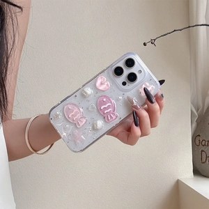 Detail of pink resin fish and pearl charms on a glittery iPhone shell with star sequins