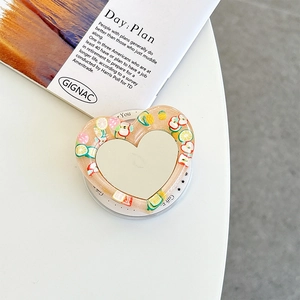 Detail of heart-shaped phone grip featuring resin fruit slices and a makeup mirror