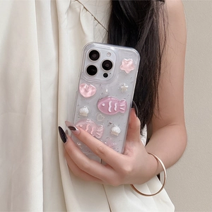Detail of pink fish and pearl 3D elements on a glittery iPhone 16 case held by a model