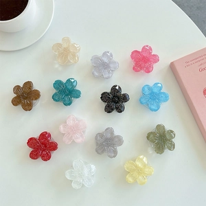 Flat lay of colorful flower phone grips with glitter resin finish on a white desk