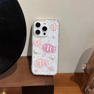 Detailed view of pink 3D shell and fish charms on a glittery iPhone case