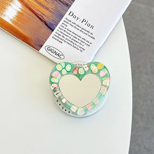 Detail of heart-shaped phone grip with mini makeup mirror and resin fruit slices