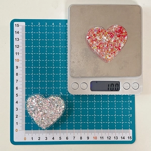 Close-up of heart-shaped resin accessories with glitter and sequins for phone grips